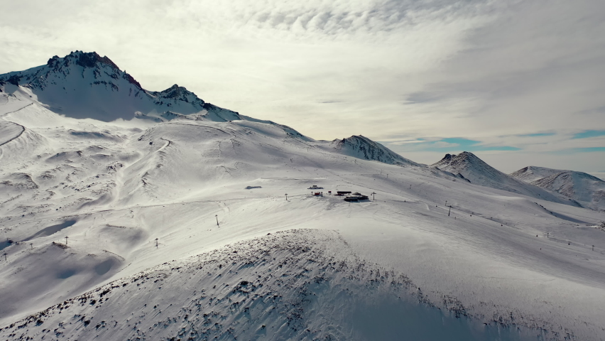 Aerial view snow mountain peak clouds in background 4k winter drone footage Ski resort. Dolly in
