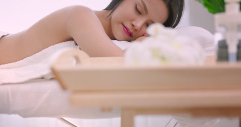 Asian Pretty young woman relaxing on bed in spa after body massage.