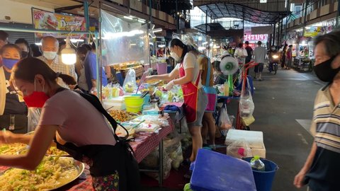 BANGKOK, THAILAND - Circa November, 2021: Customers waiting for street food at Tao Poon Fresh Local Market as female seller preparing local tasty dinner