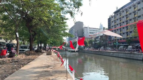 BANGKOK, THAILAND - Circa November, 2021: Colorful triangle flag pennant string near The Krungkasem Srikrung Hotel. Festival party decoration flag hang and sway beside the Phadung Krung Kasem canal