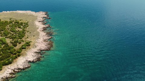 Aerial rotating view of two people swimming at Risika Beach on Krk island in Croatia