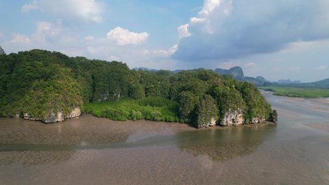 drone flying slow along the river during low tide revealing sandbars in Ao Thalane Krabi Thailand on a sunny day with mangroves and limestone mountains in the distance.