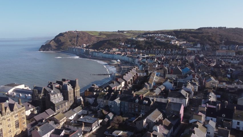 An aerial view of the the Welsh town of Aberystwyth showing the seafront. Flying backwards over the town on a sunny spring morning, Ceredigion, Wales, UK.