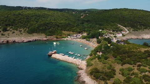 Aerial view of packed Risika Beach on Krk island in Croatia with a pirate ship in summertime