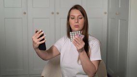 Woman is taking pills. Blue vitamins, medicines in a blister pack. Health care, treatment. Illness, disease, sick person. Female hold dietary supplement in hands. Video call to doctor.
