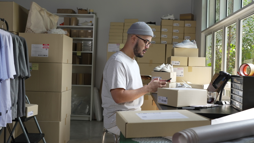 Asian male small business owner using mobile app on smartphone checking parcel box. Warehouse worker, seller holding phone scanning retail dropshipping package postal parcel bar code. | Shutterstock HD Video #1089036811