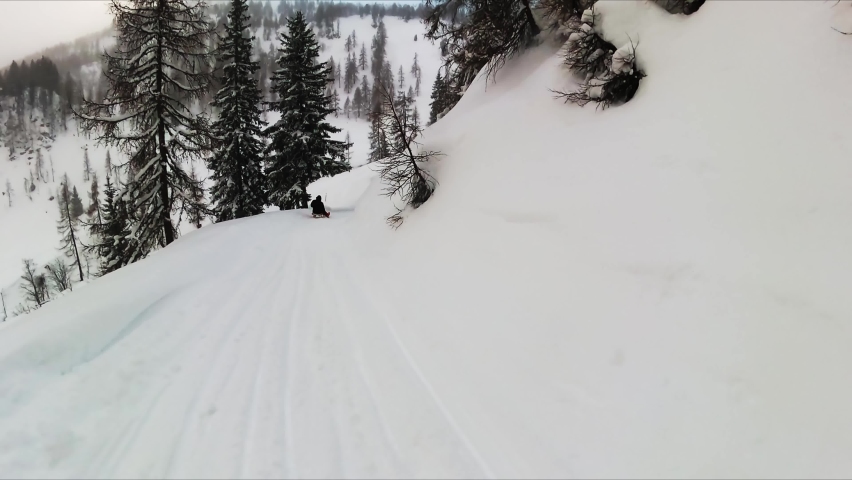 A man tobogganed down the snowy hill in winter in Obertauern, Salzburg in Austria. Hohe tauern mountain range. Bad weather condition, Snow fall. Outdoor winter activity. Fun.Sledge in the Alps, Europe