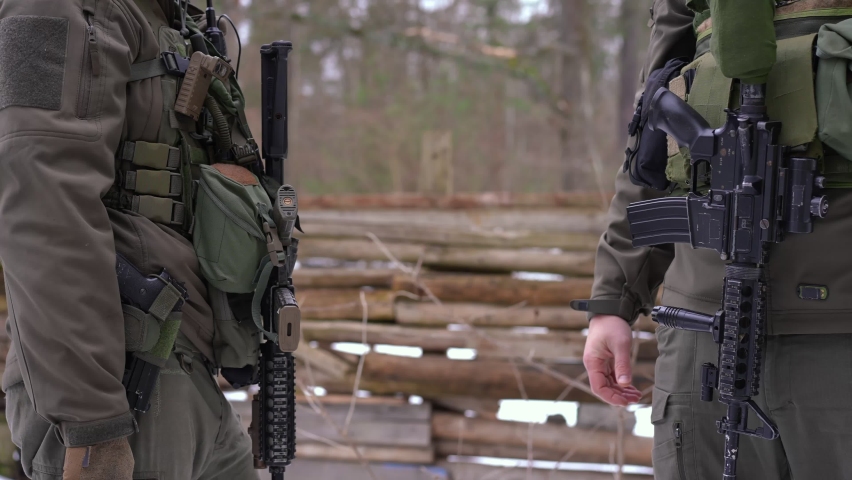 Two unrecognizable male soldiers shaking hands standing outdoors. Courageous Caucasian young men defending country independence in Ukraine in war zone. Handshake of brave warriors