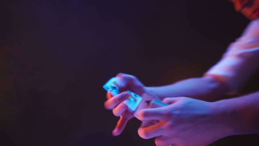 Close-up, Hands of a Magician Performing Tricks with a Deck of Cards. Neon Lighting and Smoke. Conjurer Shows Focus. Camera Quickly Rotates 360 Degrees. | Shutterstock HD Video #1089039239