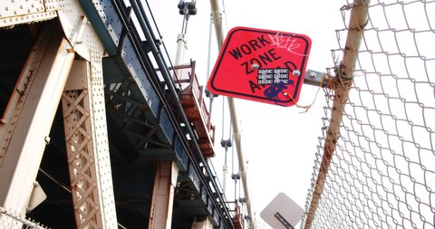 New York, New York United States - April 3,  2022: Work Zone Ahead construction sign on Manhattan Bridge.  Sign has bin vandalized with graffiti and sticker ads.