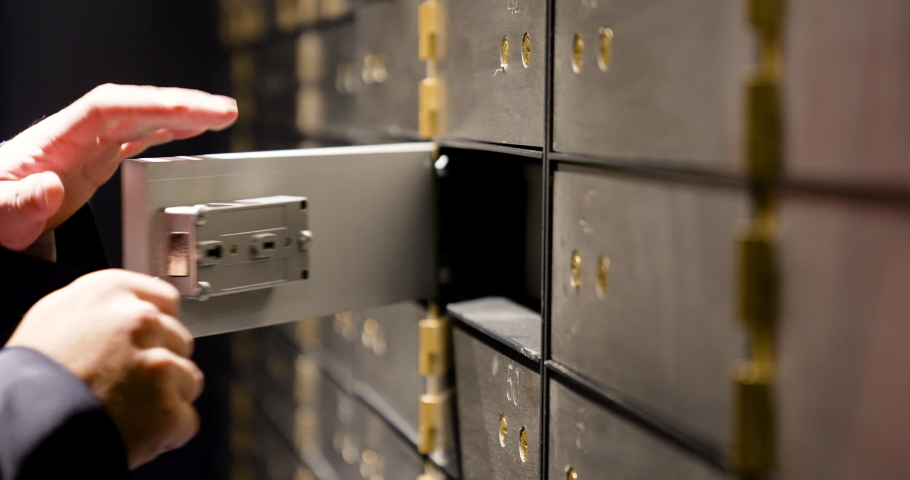 The safe deposit box in the bank vault is opened by the employee and the customer with the two keys.
The client takes out the safe to be able to extract the money and jewelry that are stored.
Security | Shutterstock HD Video #1089043945