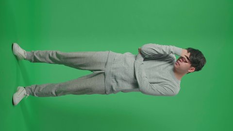 Full Body Of Asian Man Having Headache While Standing In Front Of Green Screen Background
