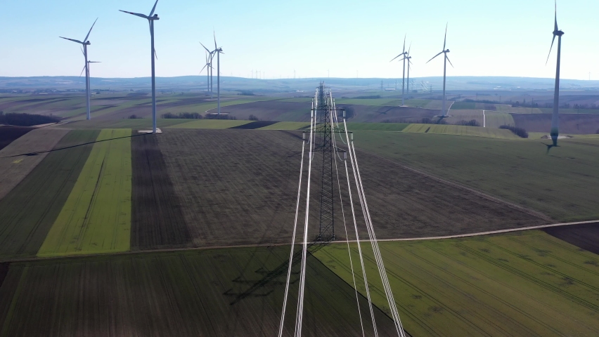 Overhead Power Line Of Transmission Tower In The Wind Farm With Wind Turbines. - aerial Royalty-Free Stock Footage #1089046519