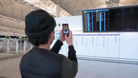 Hong Kong , Lantau Island , China - 02 20 2022: A passenger takes a photo of a screen where the airline assigned check-in desks are located at Chek Lap Kok International Airport in Hong Kong, China.