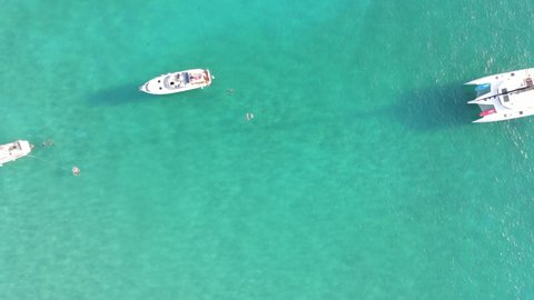 Aerial shot flying over the sea full of boats in turquoise water. Final camera movement upwards showing the horizon. Beaches of Menorca
