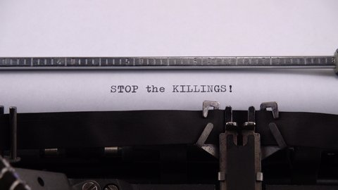 Typing phrase "STOP the KILLINGS !" on retro typewriter.
