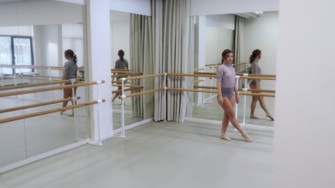 The girl dances a modern dance in a bright studio with mirrors. Slow motion, smooth motion. Graceful movements. 4K. The concept of contemporary dance.