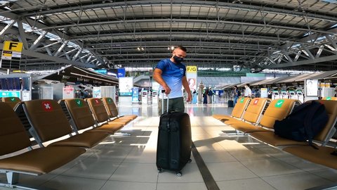 Bangkok, Thailand, 03, July, 2021:
European man travelling, man posing with luggage at Bangkok airport, young man wearing mask with luggage bag in airport lounge