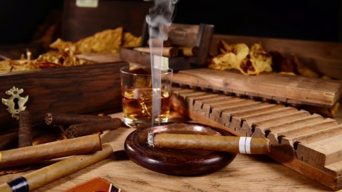 Smoking Cigar with Whisky and Tobacco Leaves on wooden Background