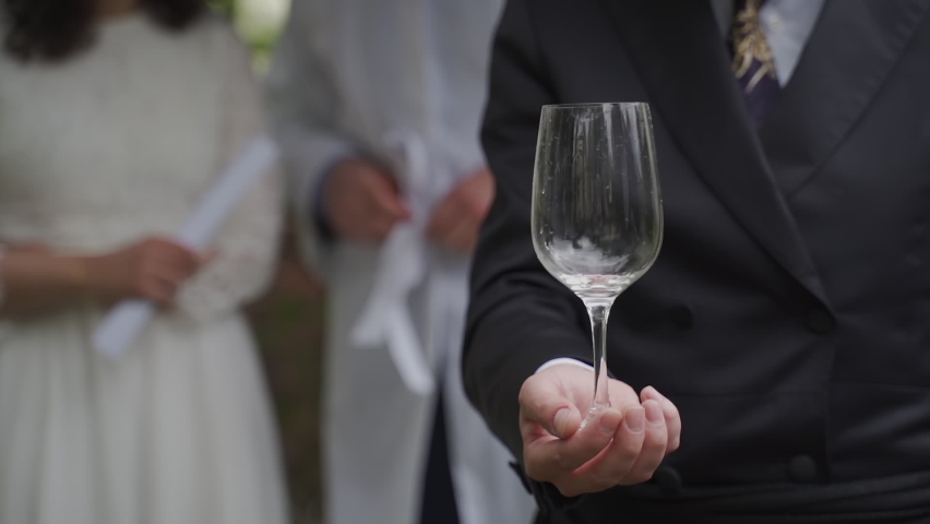 In a Jewish wedding, the couple stands under the chuppah. The rabbi, according to tradition, filled the glass with wine in full and passes it to the groom Royalty-Free Stock Footage #1089054385