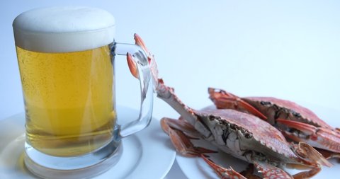 beer foam often referred to as "beer crown". bubbles of light beer foam rise to the top of a glass mug. in the background are two red boiled crabs as a beer snack