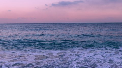 Sunset on the sea coast, sea waves, pink sky above the water