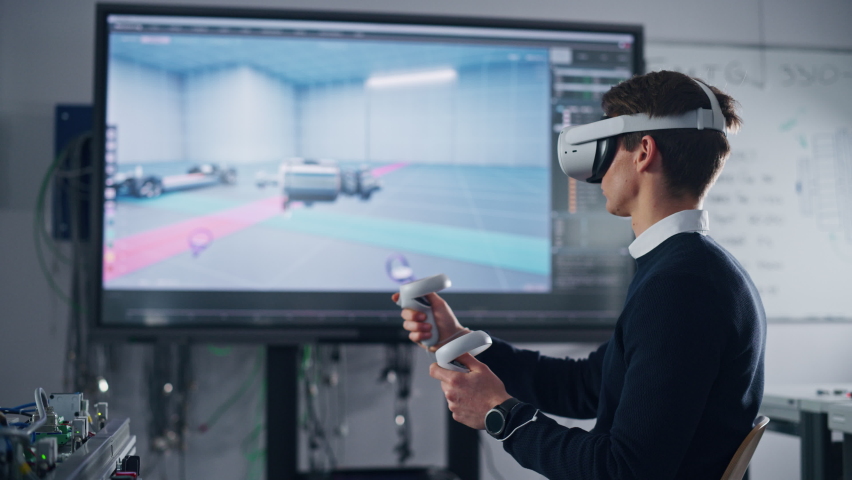 Male Student Wearing AR Headset Looking on Big Screen and Moving Controllers while Designs Prototype of Electric Motor at University. Futuristic Virtual Design of Mixed Technology Application Concept Royalty-Free Stock Footage #1089059729