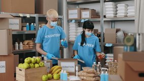 Caucasian man and woman in face masks and rubber gloves packing together cardboard boxes for donation. Volunteering and coronavirus concept. - Powered by Shutterstock - Get 15% off with code: PIKWIZARD15