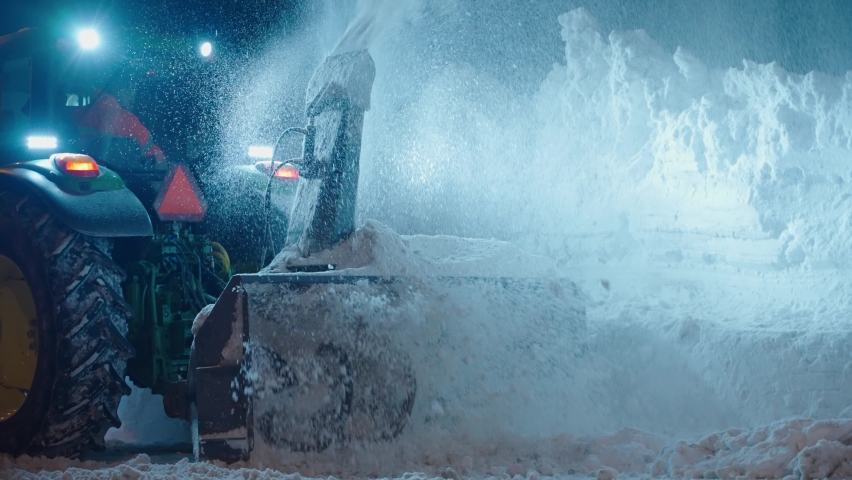 Snow plow blower truck cleaning thick snow after blizzard storm from road at night