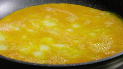 Close-up View of Person Cooking Scrambled Eggs on a Hot Frying Pan