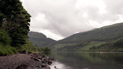 Tranquil Scottish Loch with Paddleboarder on an Overcast Day