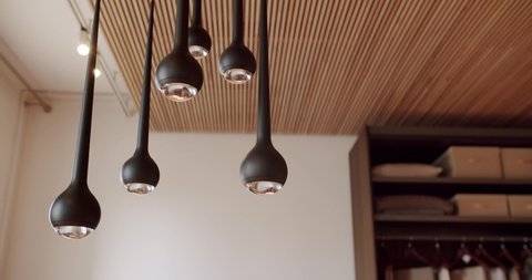 Modern black lamp suspended above it composed of several parts. minimalist design of the lamp inside the house with natural wood tile ceiling. Modern Lamp at home.