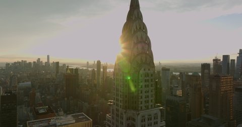 Top section of Chrysler Building with crown decoration against setting sun. Revealing tall Empire State Building. Manhattan, New York City, USA in 2021