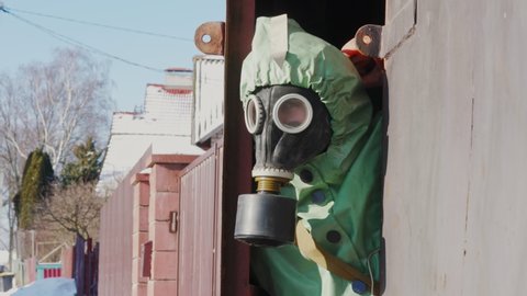 Man in respirator and protection suit looking through open metal door of bomb shelter