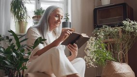 Relaxed senior woman sitting on floor and reading book indoors at home. - Powered by Shutterstock - Get 15% off with code: PIKWIZARD15
