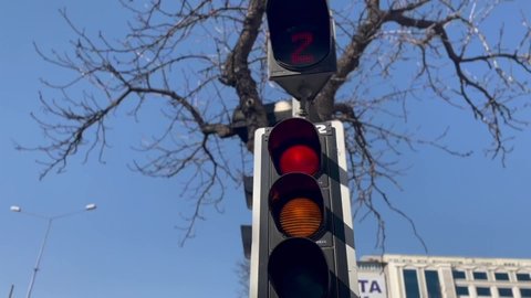 Close-up traffic light, traffic flowing in the city. Red light, yellow light, green light. Stop, get ready, move.