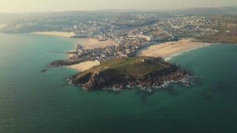 Cinematic drone and aerial footage over St. Ives. Beach in North Cornwall. Green seas and blue skies and surfers enjoying the waves