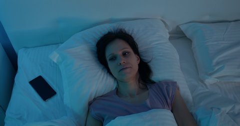 Woman lying in bed and cannot fall asleep. Female suffers from insomnia