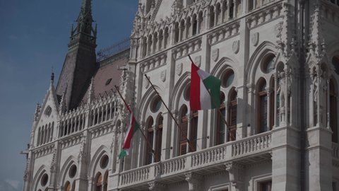 Hungarian tricolor national flag on the ornate building of the Hungarian Parliament in Budapest, Hungary. Flag of Hungary waving on wind on parliament wall. red white green flag of european country