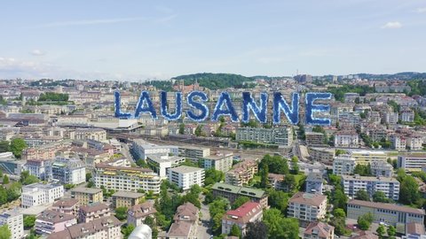 Inscription on video. Lausanne, Switzerland. Flight over the central part of the city. La Cite is a district historical centre. Blue lights form luminous. Electric style, Aerial View
