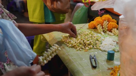 
A vendor is stringing garlands from jasmine flowers.