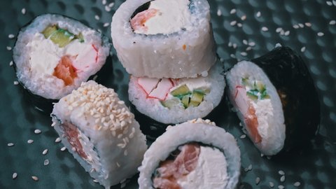 Fresh sushi roll with sesame seeds rotate close up. Sushi from fish, salmon, rice, cucumbers. Sushi restaurant, sushi delivery. Delicious Japanese food. Sliced rolls.