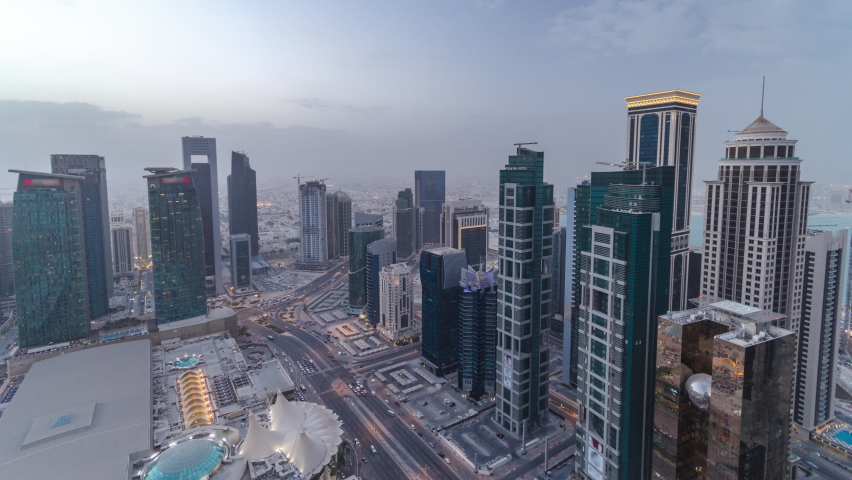 Skyline of the West Bay area from top in Doha day to night transition timelapse, Qatar. Illuminated modern skyscrapers aerial view from rooftop at evening after sunset. Traffic on the road Royalty-Free Stock Footage #1089083269