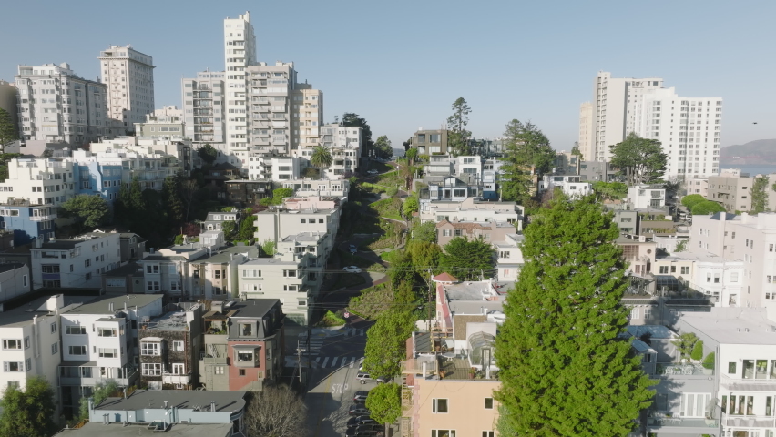 Scenic view of curving road along residential block with beautiful architecture. Aerial view of modern cityscape with lush greenery of Lombard street in San Francisco. High quality 4k footage