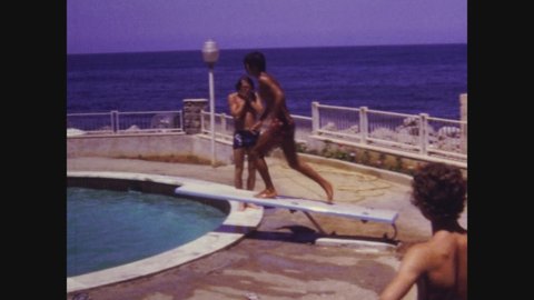 PIANO BATTAGLIA, ITALY JULY 1971: Boys jump into the pool from the diving board in 70s