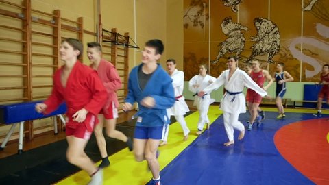 Chelyabinsk, Chelyabinsk region, Russia - 02.06.2022: Judoists, karatekas, sambists run around the gym.

Representatives of different martial arts run around the gym.