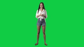 Standing young stylish woman drinking water from plastic bottle. Full body isolated on green screen background