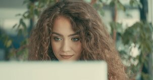 Portrait of young business woman sitting in work space, chatting to discussing communicating by video call colleagues in office. Female looking at computer on online conference. 4K slow motion