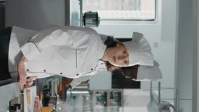 Vertical video: Authentic portrait of female chef preparing food in restaurant kitchen, making professional cuisine dish with gourmet recipe and organic ingredients. Confident woman cooking delicious