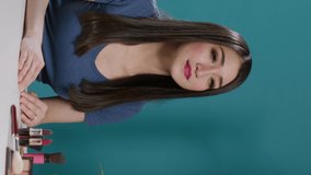 Vertical video: Young vlogger filming online video with makeup cosmetics, using vlogging camera to record videoblog. Beauty influencer broadcasting live vlog with glamour products, content. Tripod